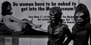 Guerrilla girls com um cartaz a dizer "as mulheres têm de estar nuas para entrarem no museu?